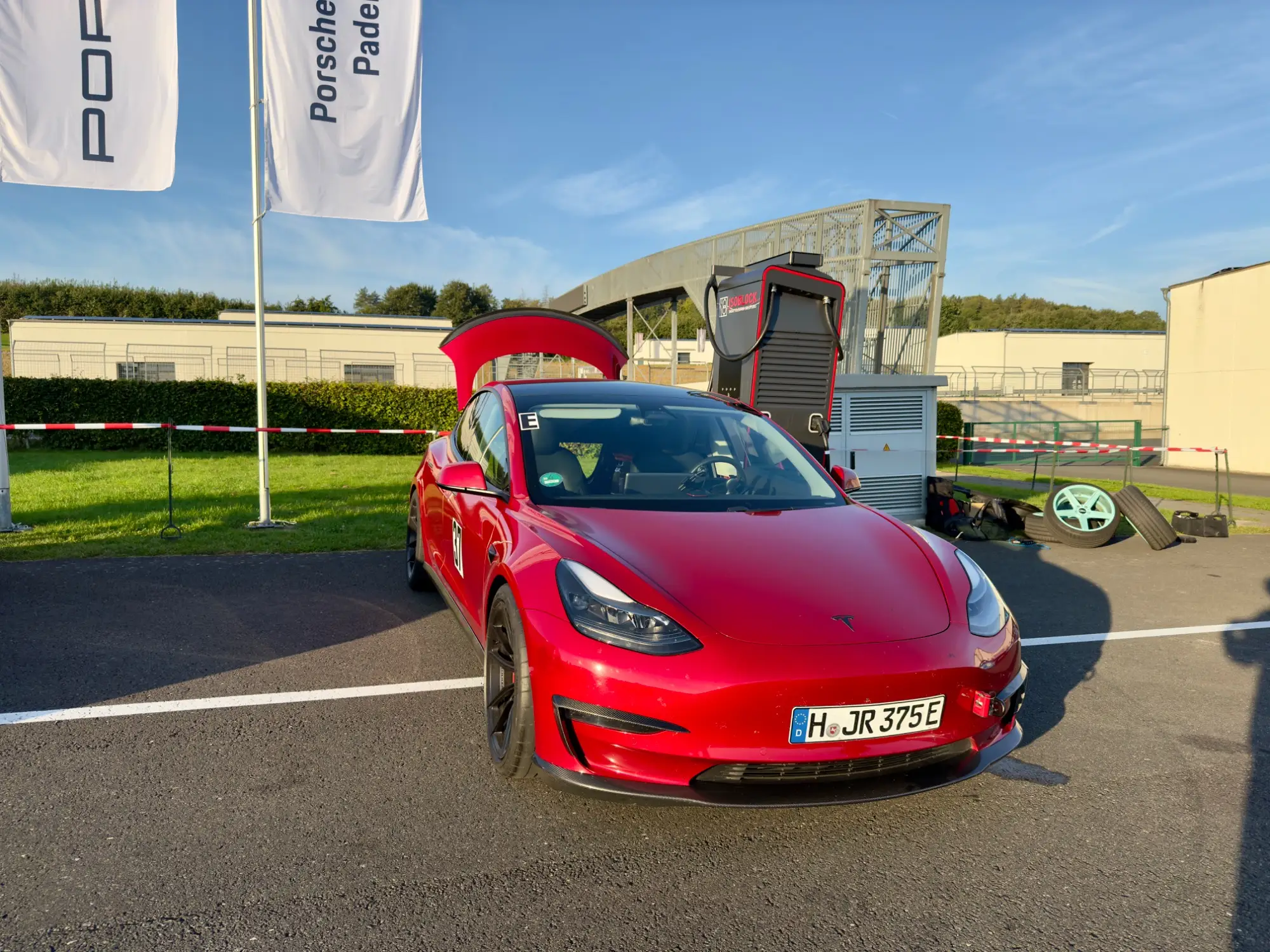 Rotes Tesla Model 3 Performance „Red Devil“ mit geöffnetem Frunk, geparkt im Fahrerlager, Bilster Berg, 22. September 2024.