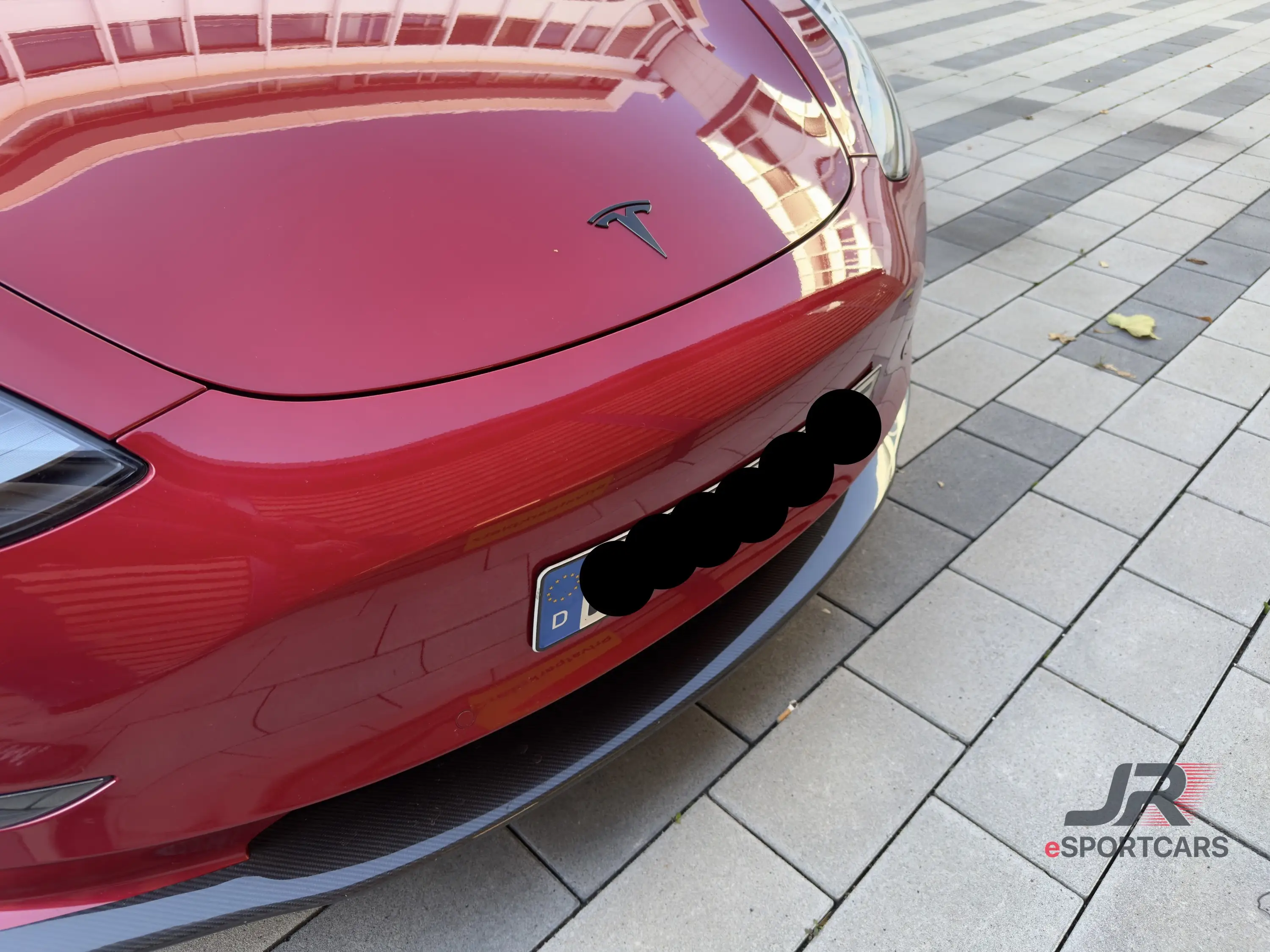 Front mit schwarzem Tesla-Logo, das Kennzeichen ist unkenntlich gemacht.