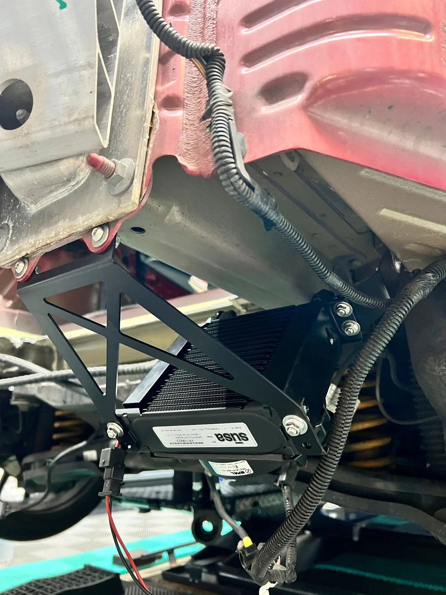 Blick unter das Auto: zusätzlicher Kühler für den hinteren E-Motor in einer schwarzen Halterung.