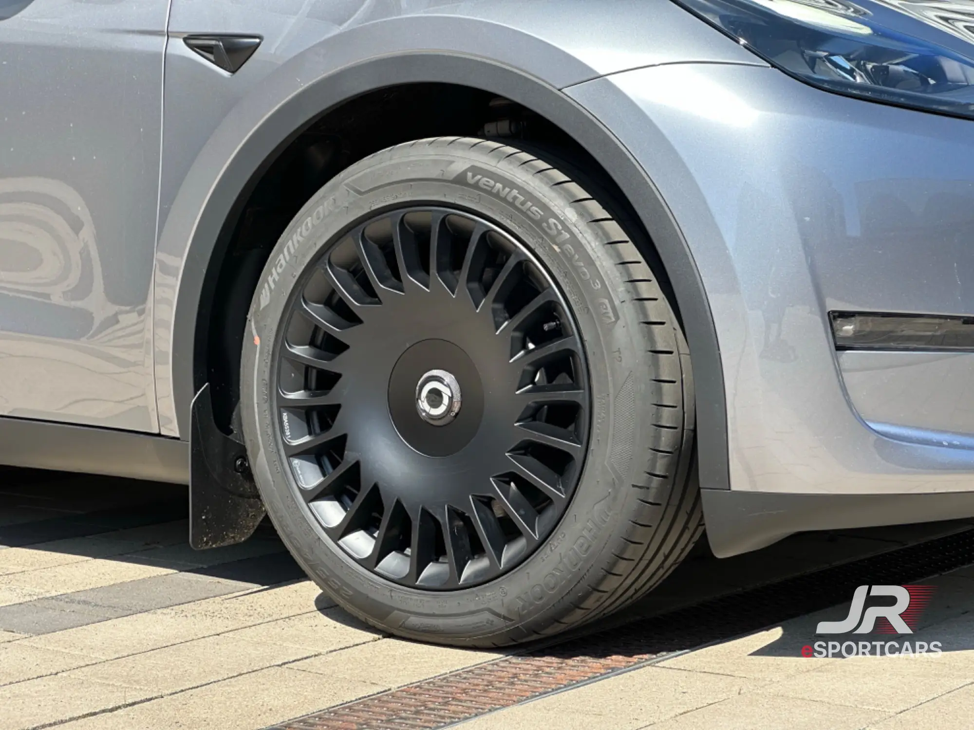 Vorderrad und Seite des silbergrauen Tesla Model Y Long Range „Silver Star“.